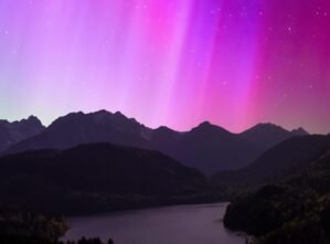 Breathtaking view of the aurora borealis illuminating the night sky over a serene mountain lake.